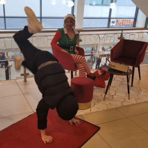 Weihnachtselfe bei ihrer Elfensprechstunde in Ebersberg während ein junger Besucher einen Handstand macht.