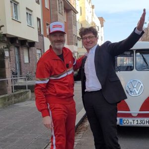 Lachender Moderator und Chauffeur. Duo begrüßt Gäste zur Bulli Laugh Tour Nürnberg