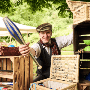 Lächelnder Künstler Hannes Hoffmann zeigt Jonglierkeule beim Mitmachzirkus für Familien.