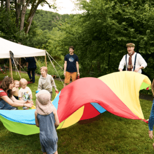 Kinder und Künstler beim gemeinsamen Schwungtuch-Spiel in Franken auf einer Wiese.