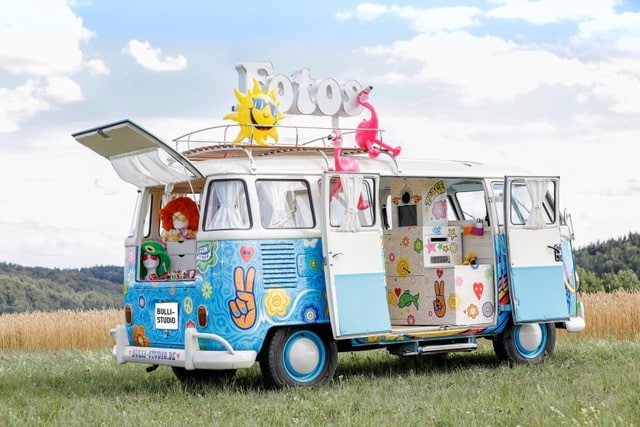 Blauer VW T1 Fotobulli im Hippie- und Flower-Power-Stil auf einer Wiese - mobile Fotobox für Events.
